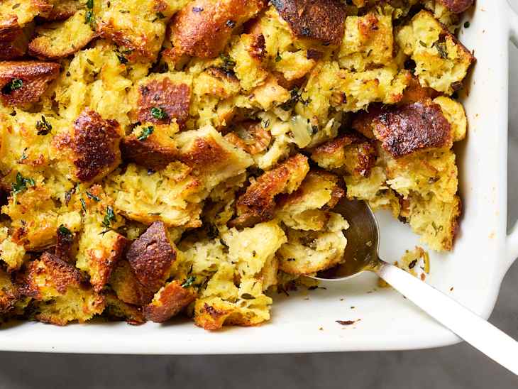 overhead shot of thanksgiving stuffing in a white baking dish, with some of the stuffing taken out of the bottom right corner of the dish.
