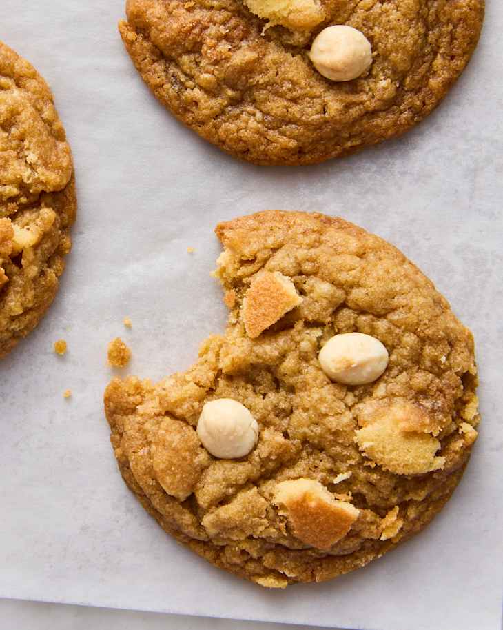 Chewy cookies with white chocolate chips and pieces of vanilla wafers on parchment paper.