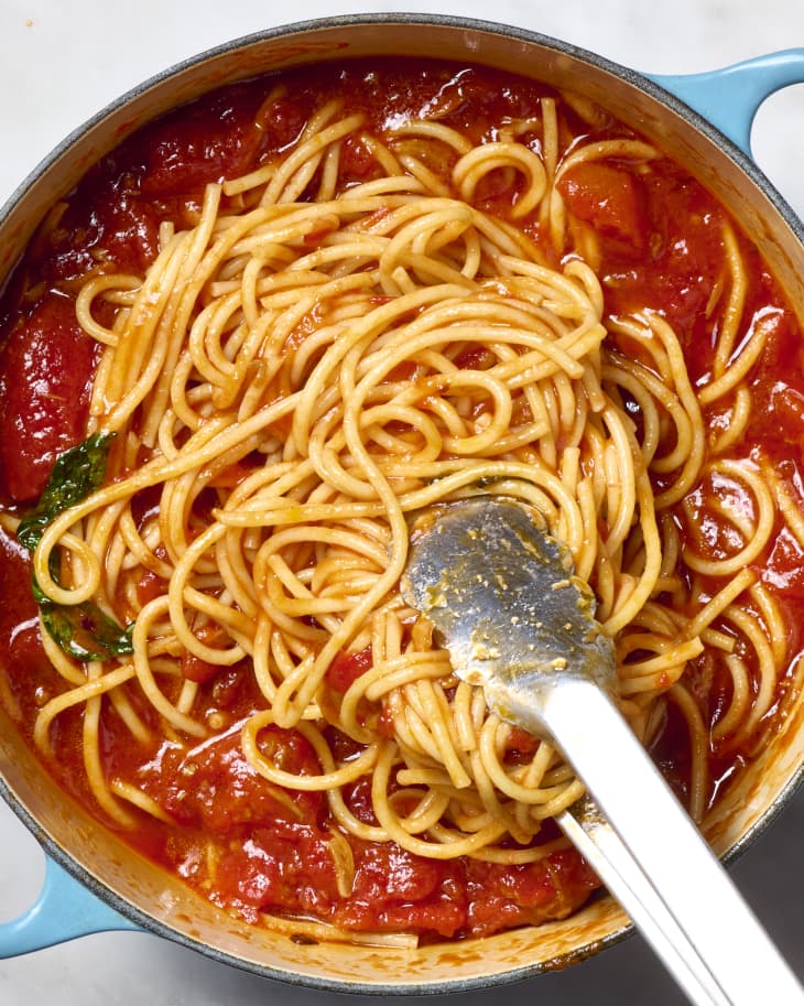 overhead shot marinara in a large pot with the spaghetti being added