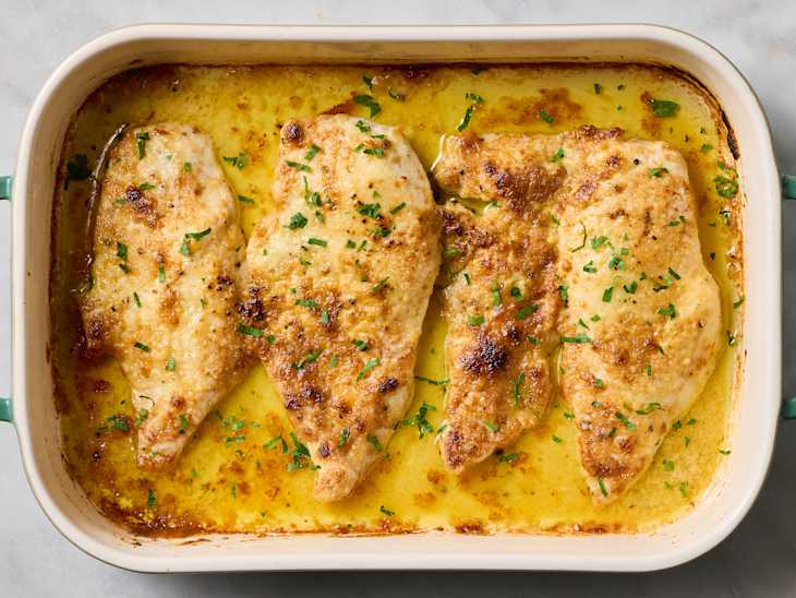 Pan-seared chicken fillets garnished with chopped herbs, golden brown and juicy.