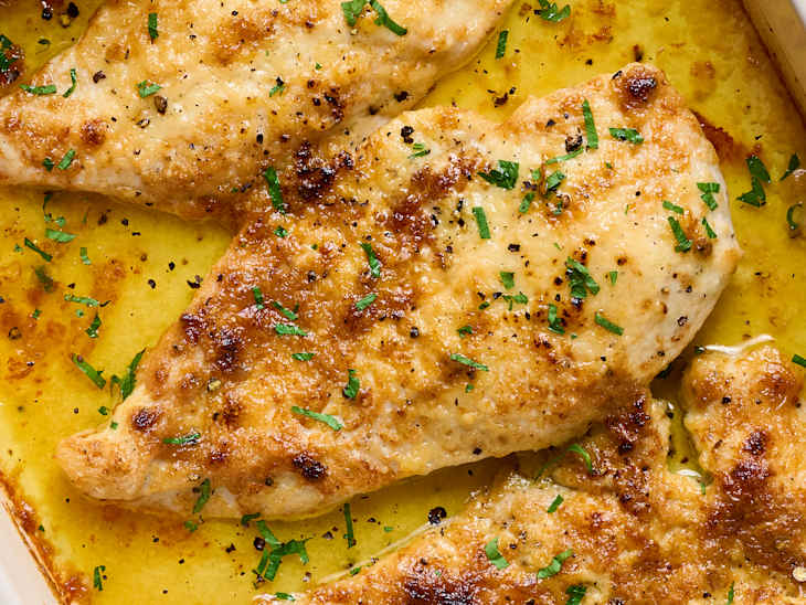 Pan-seared chicken fillets garnished with chopped herbs, golden brown and juicy.