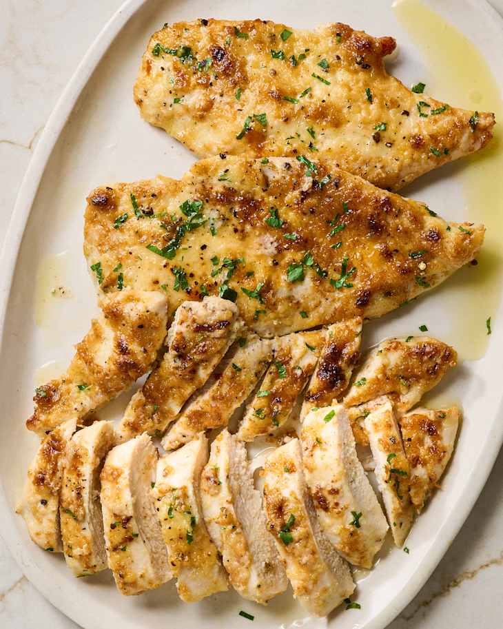 Pan-seared chicken fillets garnished with chopped herbs, golden brown and juicy.