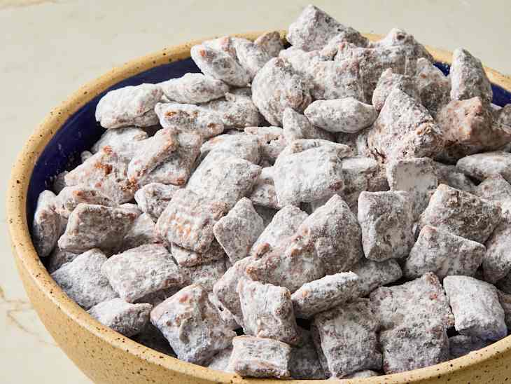 Bowl filled with powdered sugar-coated chocolate snack pieces, arranged in a rustic dish.