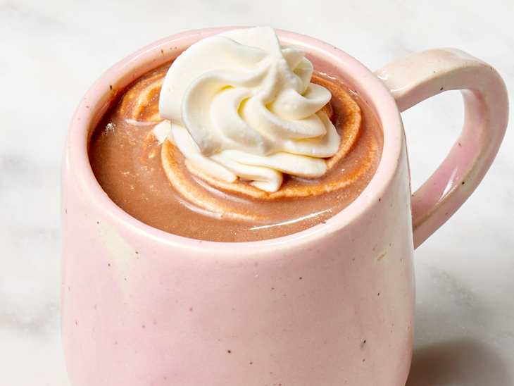 Angled shot of Ree Drummond's hot chocolate recipe in a pink mug, topped with whipped cream.