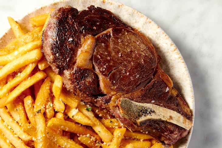 steak on a plate with a side of french fries AKA Steak Frites