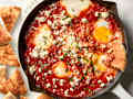 overhead shot of shakshuka in a white cast iron with pita being dipped into it