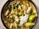 Bowl of chicken soup with shredded chicken, white beans, corn, green chilies, cilantro, and a dollop of sour cream, garnished with lime.