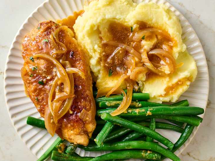 Grilled chicken breast topped with sautéed onions, served with creamy mashed potatoes and green beans.