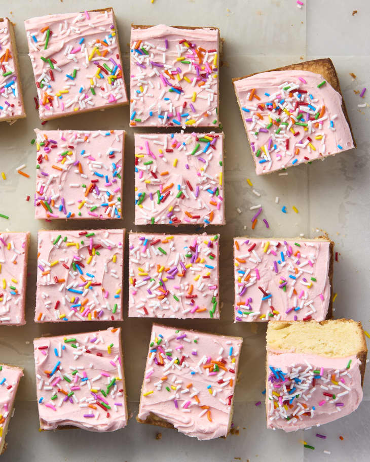 An overhead view of sour cream bar cookies with pink frosting and rainbow sprinkles