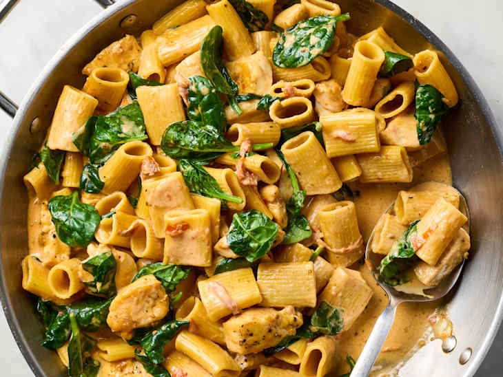 Tuscan chicken rigatoni in a skillet with a spoon
