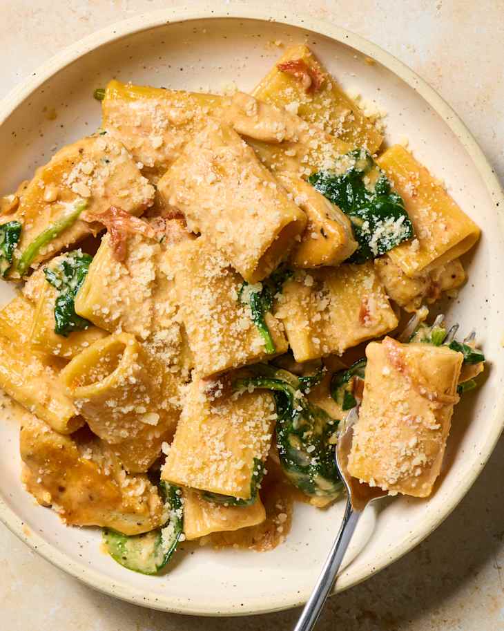 Tuscan chicken rigatoni in a bowl with a fork