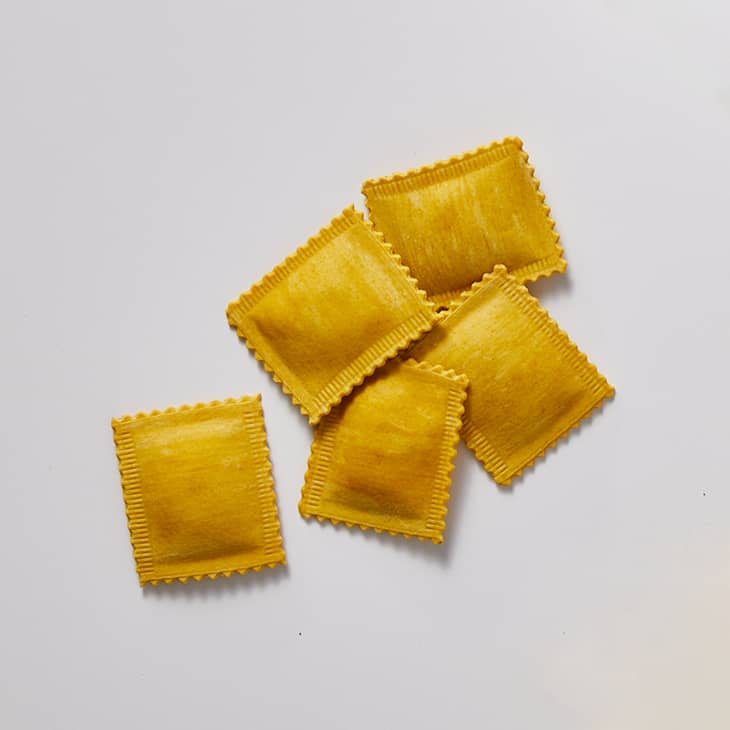 Square ravioli on a white surface.