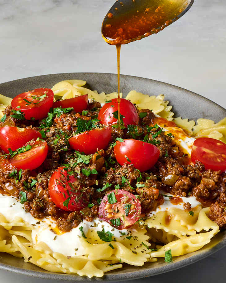 overhead shot of yalanci manti in a grey bowl, topped with herbs