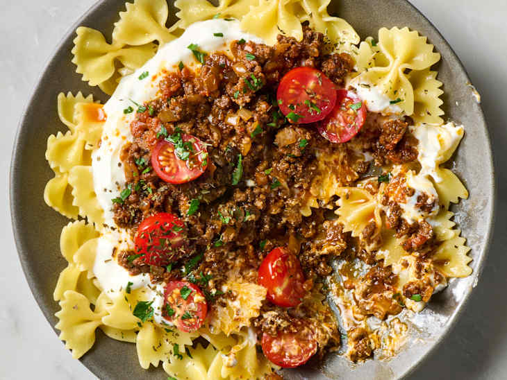 overhead shot of yalanci manti in a grey bowl, topped with herbs